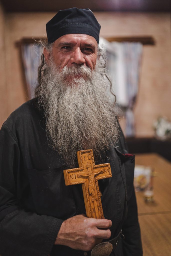 Portrait orthodoxer Mönch mit langem weißem Bart und Holzkreuz in der Hand